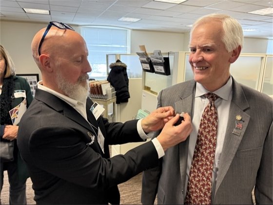 Mayor Matt Jessop provides an OWATONNA pin to Representative Tom Sexton.