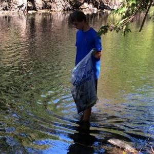 Young man standing in water looking for garbage